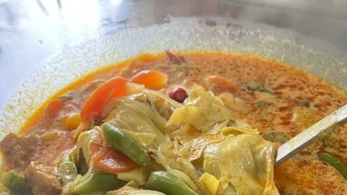 Semangkuk kuah lontong pekat bersama sayur dan tempe