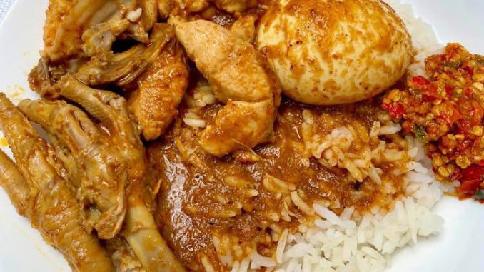 Gulai ayam Terengganu dengan kuah pekat dalam mangkuk, disusun bersama nasi minyak dan ulam