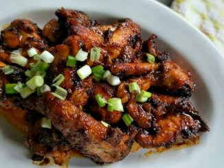 Ayam goreng madu berkilat dalam kuali, disalut dengan sos merah pekat dan madu