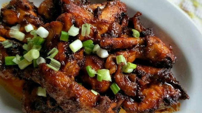 Ayam goreng madu berkilat dalam kuali, disalut dengan sos merah pekat dan madu