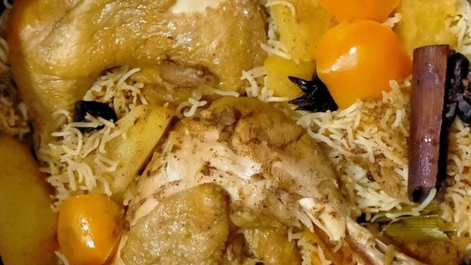 Nasi ayam bersama ayam rebus dan air asam kerisik dalam pinggan, dihias dengan hirisan tomato dan daun ketumbar