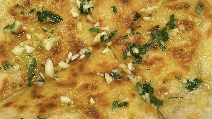 Roti naan cheese homemade disapu garlic butter dan dipotong segi tiga atas pinggan putih