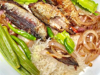 Ikan rebus goreng keemasan atas pinggan dengan taburan bawang dan cili padi, dimakan dengan nasi panas