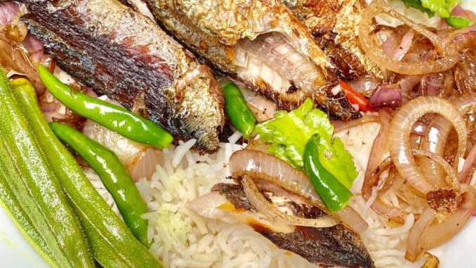 Ikan rebus goreng keemasan atas pinggan dengan taburan bawang dan cili padi, dimakan dengan nasi panas
