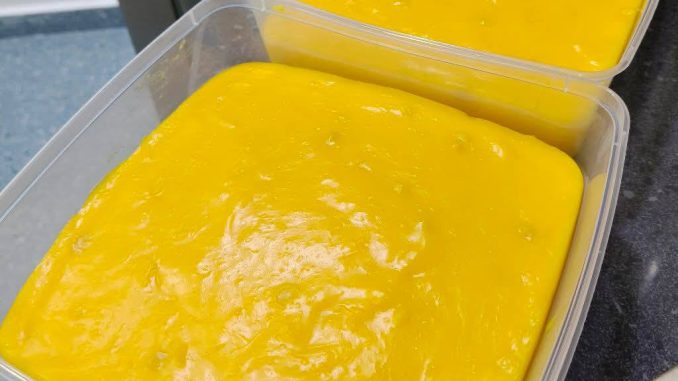 Puding kastard jagung berwarna kuning lembut yang dipotong dalam bekas