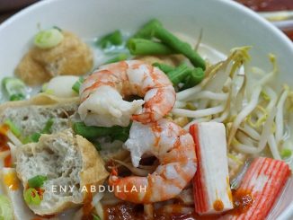 Semangkuk white mee curry Penang dengan kuah putih santan, sambal cili dan isi makanan laut
