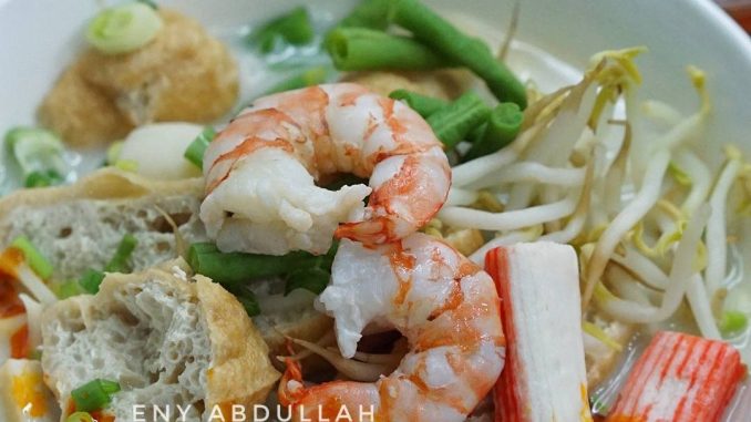 Semangkuk white mee curry Penang dengan kuah putih santan, sambal cili dan isi makanan laut