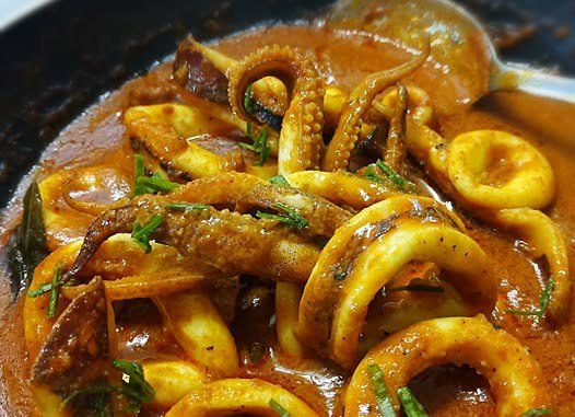 Hidangan rendang sotong berkuah pekat dengan daun kunyit dalam pinggan