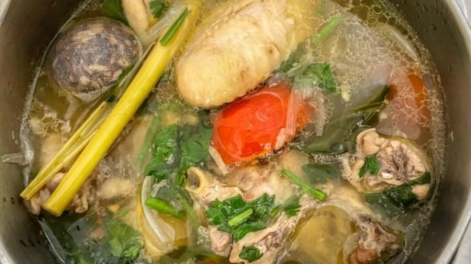 Semangkuk sup ayam Thai dengan lobak merah, tomato dan daun limau purut