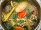 Semangkuk sup ayam Thai dengan lobak merah, tomato dan daun limau purut