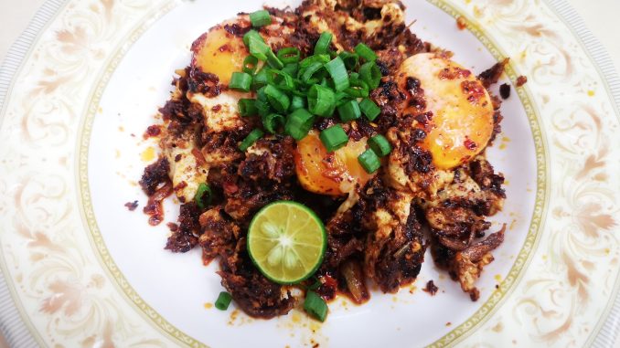 Telur sambal cili kering yang pedas dan menyelerakan, dihias dengan daun bawang dan perahan limau.