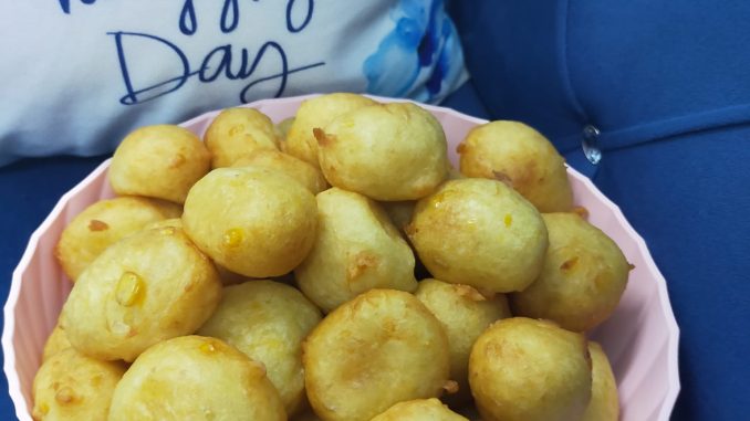 Cekodok jagung keemasan tersusun di atas pinggan, kelihatan rangup dan berkilat, sesuai untuk minum petang.