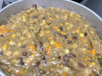 Bubur Asyura Utara pekat dan berkilat, dihidang dalam mangkuk putih dengan daun pandan sebagai hiasan.