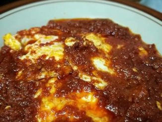 Sambal telur pecah pedas berwarna merah pekat dihidang bersama nasi putih panas