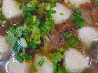 Semangkuk sup bebola ayam bersama isi ayam, daun ketumbar dan bawang goreng