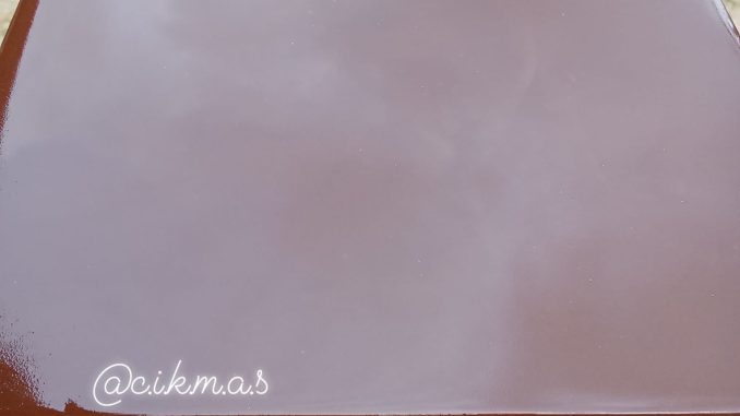 Puding coklat berkilat dan sejernih kaca disusun cantik atas pinggan putih, dihias dengan parutan coklat.