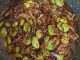 Sambal ikan bilis petai siap dimasak, berwarna merah pekat dengan petai dan ikan bilis goreng, dihidang dalam pinggan putih.