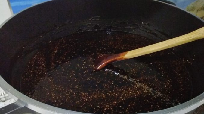 Kuah rojak pekat berwarna gelap dengan bijan dan kacang kisar, disimpan dalam bekas besar.