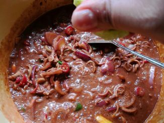 Budu campur dengan hirisan bawang, cili, bunga kantan dan limau dalam mangkuk putih.