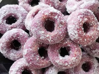 Kuih keria keledek ungu disalut gula putih, tersusun dalam pinggan untuk hidangan minum petang.