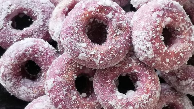 Kuih keria keledek ungu disalut gula putih, tersusun dalam pinggan untuk hidangan minum petang.