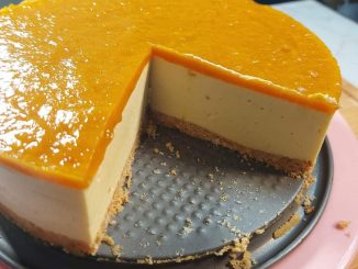 Mango Cheesecake Harum Manis berlapis biskut rangup dan puri mangga kuning keemasan di atas, dihias dengan potongan mangga segar.