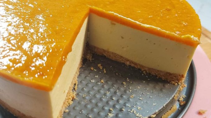 Mango Cheesecake Harum Manis berlapis biskut rangup dan puri mangga kuning keemasan di atas, dihias dengan potongan mangga segar.