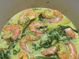 Gulai lemak udang berkuah pekat dengan pucuk paku pakis yang segar, cili padi, santan dan serai, siap untuk dihidang bersama nasi panas.