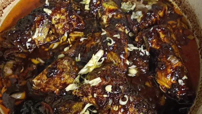 Ikan masak taucu pedas siap dimasak dalam pinggan – lauk kampung sedap dengan kuah taucu pekat dan ikan goreng garing.
