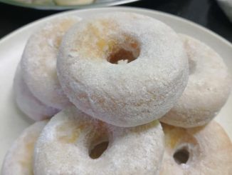 Donut gebu keemasan, tersusun kemas atas pinggan putih, siap untuk dihidang.
