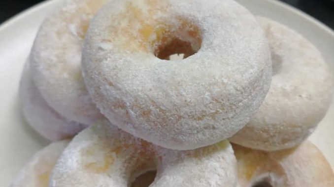 Donut gebu keemasan, tersusun kemas atas pinggan putih, siap untuk dihidang.