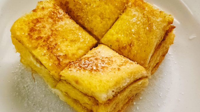 Roti telur goreng keemasan di atas pinggan putih