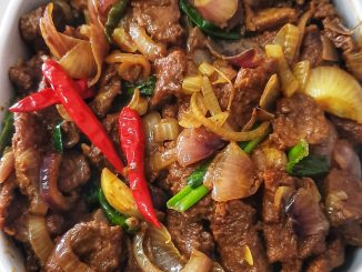 Daging goreng kunyit basah berwarna keemasan dengan hirisan bawang dan cili