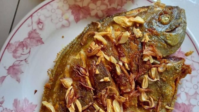 Ikan bawal segar dibersihkan dan dikelar sebelum digoreng