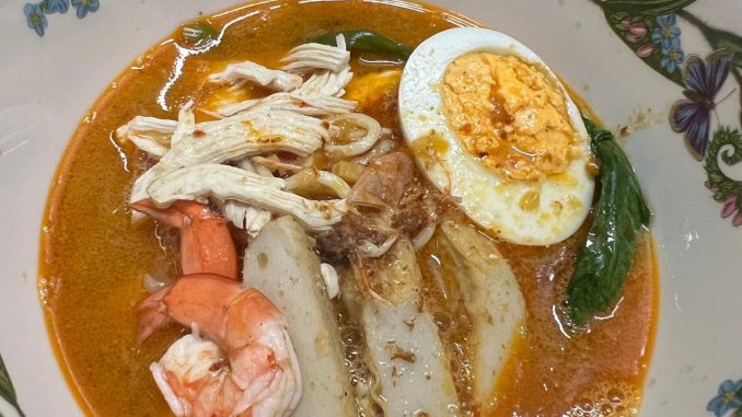 Mee udang simple dihidangkan dengan kuah pekat berwarna merah, udang segar, mi kuning, kangkung, fish cake dan telur rebus.