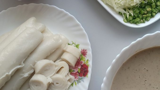 Laksam Kelantan tradisional digulung lembut dan dihidangkan bersama kuah lemak ikan pekat, sambal jantan serta ulam-ulaman segar.