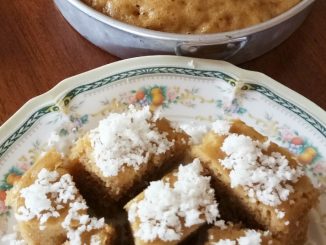 Apam gula Melaka gebu berwarna coklat dipotong dan dihidangkan bersama kelapa parut putih di atas pinggan tradisional