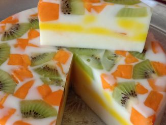 Puding buah-buahan berlapis cantik dengan agar-agar putih, lapisan kuning dan buah segar seperti strawberi, anggur dan kiwi