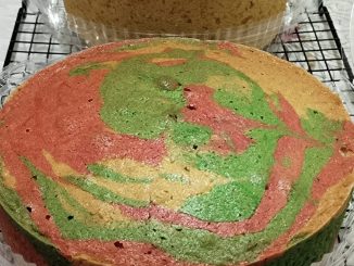 Kek marble kampung gebu dengan corak berwarna-warni dipotong dan dihidangkan di atas pinggan sesuai untuk minum petang