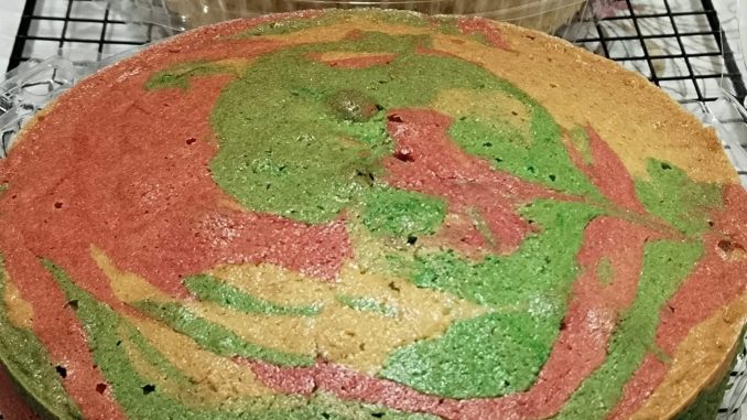 Kek marble kampung gebu dengan corak berwarna-warni dipotong dan dihidangkan di atas pinggan sesuai untuk minum petang