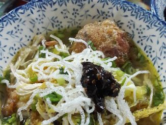Bihun soto dihidangkan dalam mangkuk bersama ayam goreng, begedil, sambal kicap, kubis, daun sup dan bawang goreng