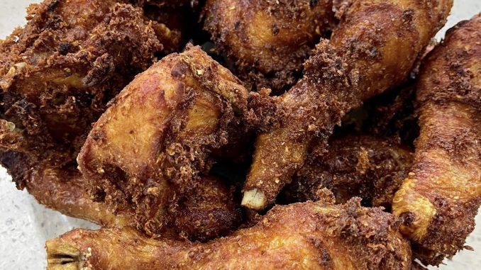 Ayam goreng berempah ketumbar berwarna keemasan dan rangup dihidangkan di atas pinggan dengan serdak rempah yang garing