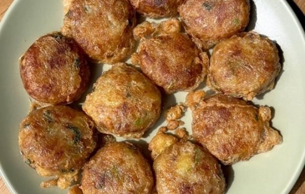 Begedil kentang goreng berwarna keemasan, rangup di luar dan lembut di dalam, dihidangkan panas dengan taburan daun sup